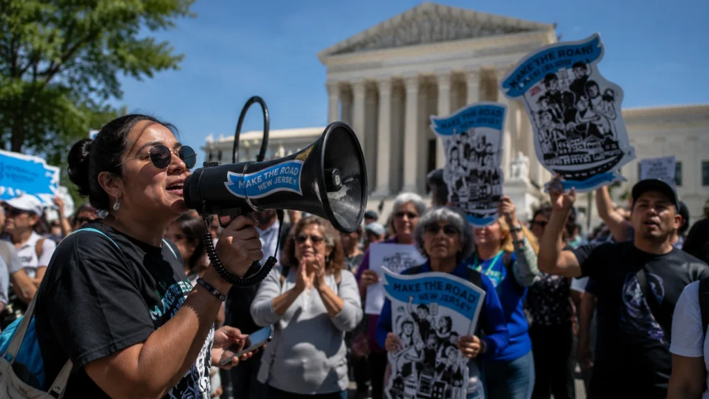 A crowd of immigration advocates holds signs and listens to a speaker with a megaphone outside the U.S. Supreme Court during a rally supporting birthright citizenship